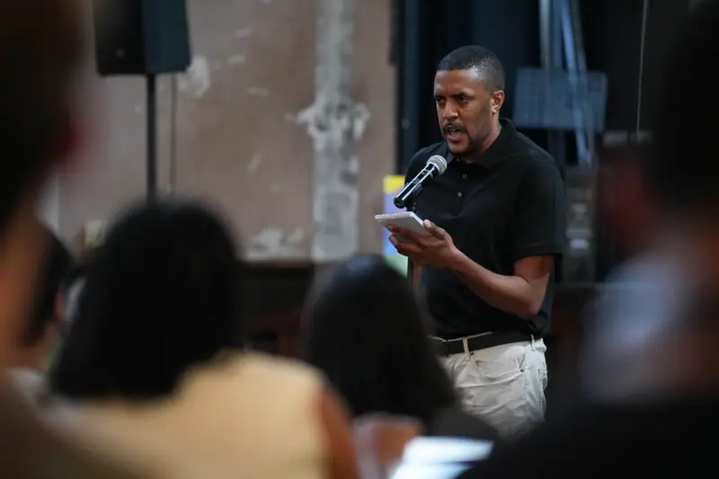 A storyteller reads his story from a page into a microphone.