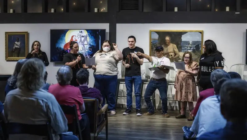 Storytellers perform together in a gallery space while the audience watches.