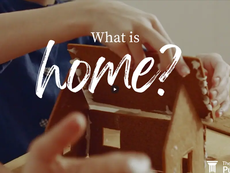 Hands holding the roof of a small gingerbread house, with the words "What is home?".